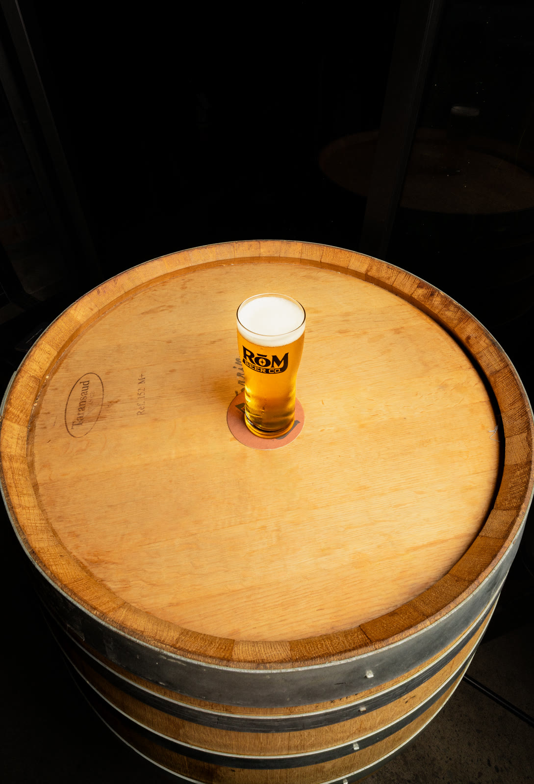 A beer can centered on a wooden barrel, photographed from above.