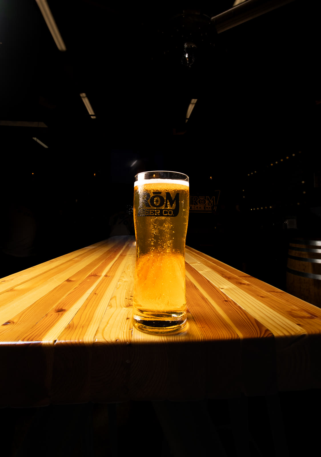 A low-angle view of a glass of beer on a wooden table.