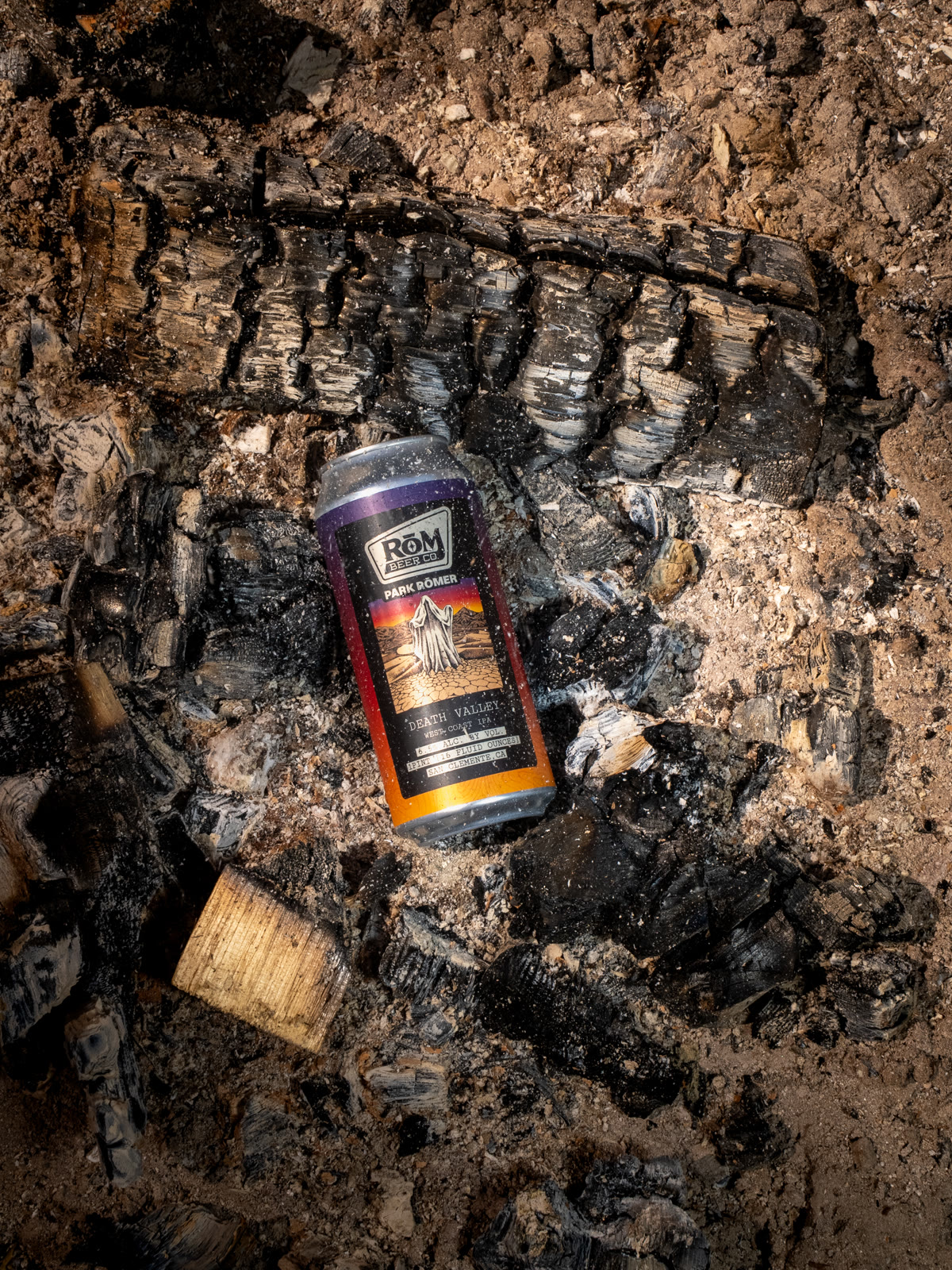 A beer can photographed against textured tree bark outdoors.